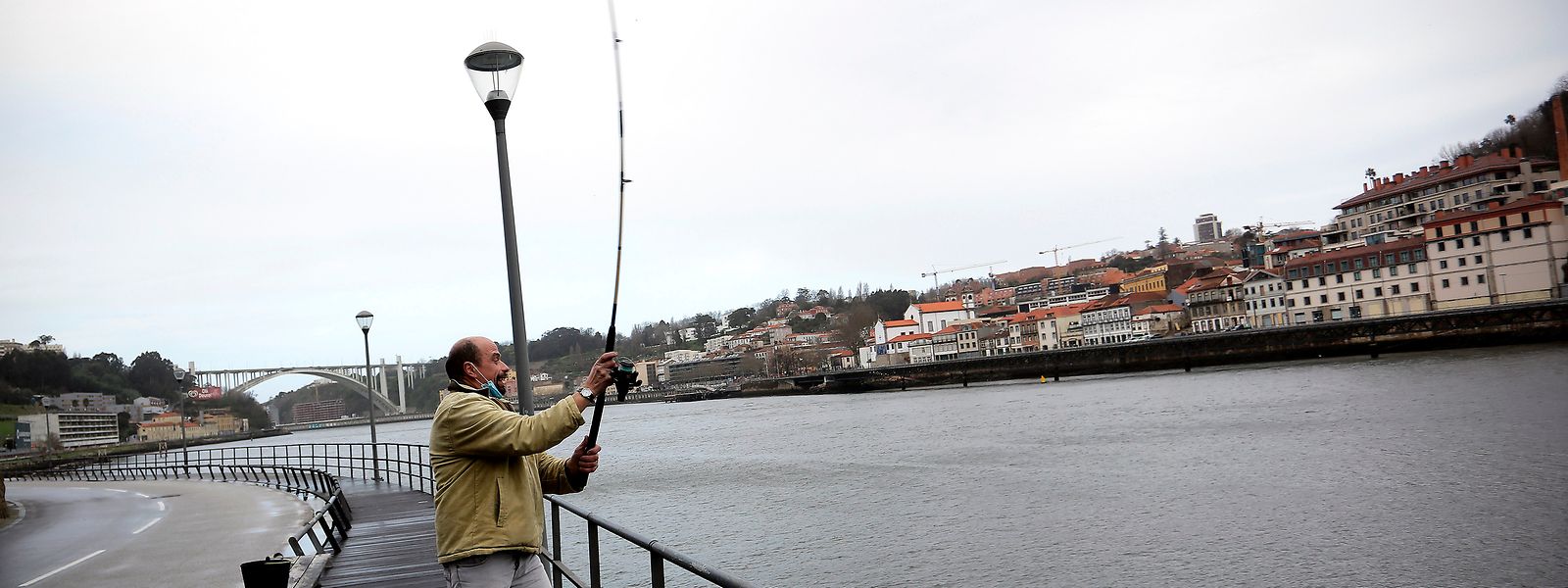Homem pesca junto ao Rio Douro, na cidade do Porto.