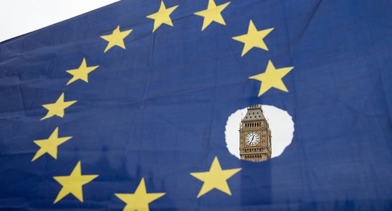 (FILES) In this file photo taken on March 29, 2017 A pro-remain protester holds up an EU flag with one of the stars symbolically cut out in front of the Houses of Parliament shortly after British Prime Minister Theresa May announced to the House of Commons that Article 50 had been triggered in London on March 29, 2017. - British and European Union negotiators have reached a draft agreement on Brexit, Prime Minister Theresa May's office said on November 13, 2018. (Photo by OLI SCARFF / AFP)
