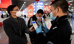 (FILES) This file photo taken on February 28, 2020 shows a passenger wearing a face mask as he shows a green QR code on his phone to show his health status to security upon arrival at Wenzhou railway station in Wenzhou. - To enter many offices, restaurants, parks or malls in China nowadays, people must show an app based on their travel history to determine if they're a coronavirus threat. (Photo by NOEL CELIS / AFP) / To go with AFP story China-Health-Virus-IT, FOCUS by Ludovic EHRET