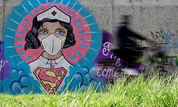 A cyclist drives past a graffiti painted by artist Kai 'Uzey' Wohlgemuth featuring a nurse as Superwoman on a wall in Hamm, western Germany, on April 8, 2020 refering to the spread of the novel coronavirus COVID-19. (Photo by Ina FASSBENDER / AFP)