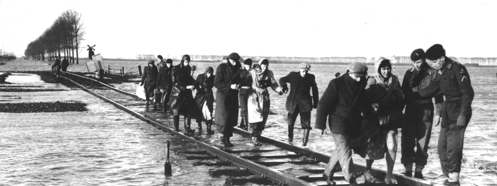 Bewohner des niederländischen Überschwemmungsgebietes in Zeeland bringen sich über einen Schienenstrang in Sicherheit. Die Sturmflut durchbrach am 1. Februar zahlreiche Deichbefestigungen und forderte mehr als 1.600 Opfer. 