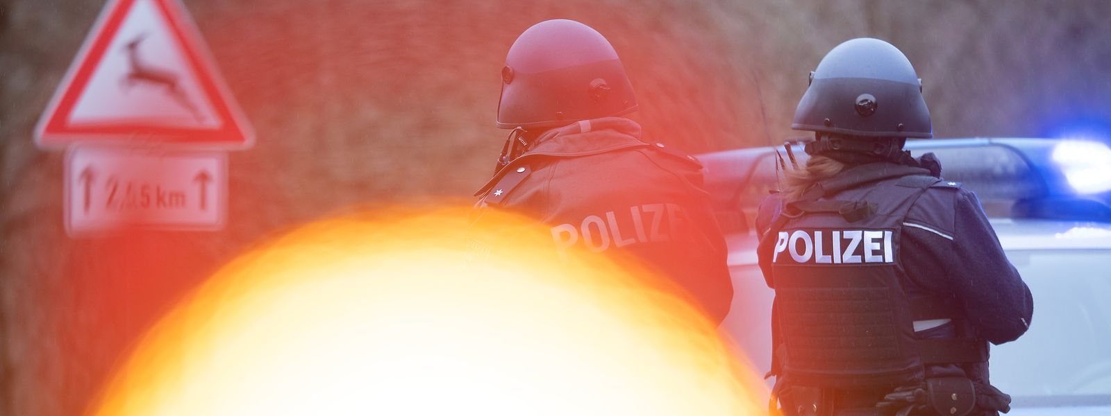 Polizeibeamte stehen an einer Absperrung an der Kreisstraße 22, rund einen Kilometer vom Tatort entfernt.