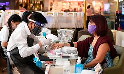 A customer gets manicure done at the Ambience mall as places of religious worship, hotels, restaurants and shopping malls are allowed to operate again after more than two months of lockdown imposed as a preventive measure against the COVID-19 coronavirus in New Delhi on June 8, 2020. (Photo by Prakash SINGH / AFP)