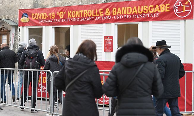 People queue to show proof of their vaccination status at the entrance to the Christmas market in Salzburg, Austria, on Friday