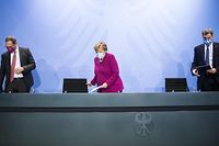 A chanceler Angela Merkel, o mayor de Berlim, Michael Mueller (à esquerda), e o presidente do Estado da Bavária, Markus Soeder, (à direita) na conferência de imprensa sobre a situação da crise sanitária no país, esta quarta-feira. 