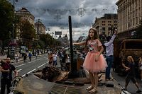 Um menina em cima de um tanque russo destruído, nas ruas de Kiev, no sábado.