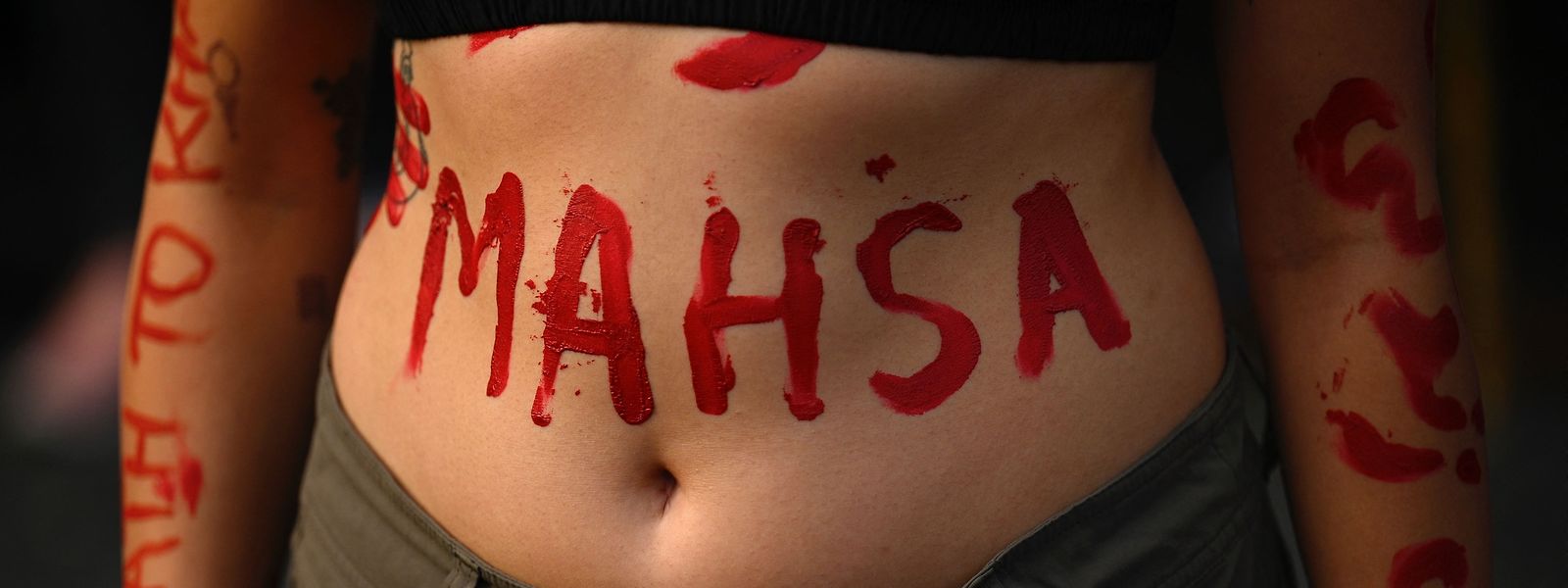 Une militante porte le nom de Mahsa Amini peint sur son corps lors d'une manifestation contre sa mort.