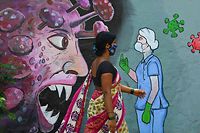 TOPSHOT - A pedestrian walks past a wall mural depicting a frontline medical staff stopping the Covid-19 coronavirus, in Navi Mumbai on June 7, 2021. (Photo by Indranil MUKHERJEE / AFP)