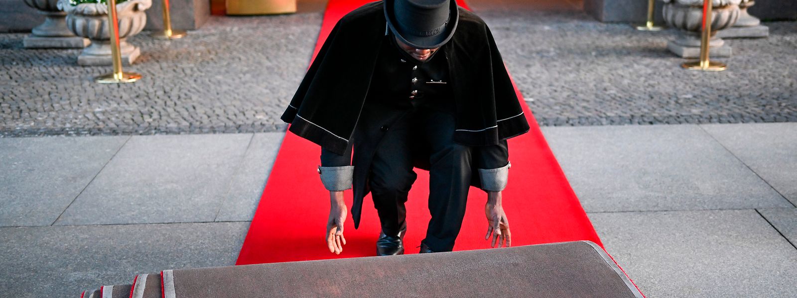Doorman Timothy Uhunamure rollt vor dem Hotel Adlon den roten Teppich aus. Insidern zufolge wird König Charles III. wohl dort unterkommen, wo bereits seine Mutter Queen Elizabeth II. zu Gast war.