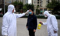 (FILES) This file photo taken on February 28, 2020 shows shows a factory employee being disinfected and his temperature taken by security guards in protective gear at the entrance of the Azure Eyeglasses Company in Wenzhou. - China's economy contracted for the first time in decades last quarter as drastic measures to contain the coronavirus pandemic brought activity to a standstill, official data showed on April 17, 2020. (Photo by NOEL CELIS / AFP) / TO GO WITH AFP STORY HEALTH-VIRUS-CHINA-ECONOMY-MANUFACTURING,FOCUS BY DAN MARTIN