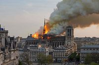 TOPSHOT - Smoke billows as flames burn through the roof of the Notre-Dame de Paris Cathedral on April 15, 2019, in the French capital Paris. - A huge fire swept through the roof of the famed Notre-Dame Cathedral in central Paris on April 15, 2019, sending flames and huge clouds of grey smoke billowing into the sky. The flames and smoke plumed from the spire and roof of the gothic cathedral, visited by millions of people a year. A spokesman for the cathedral told AFP that the wooden structure supporting the roof was being gutted by the blaze. (Photo by Fabien Barrau / AFP)