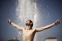 TOPSHOT - A man refreshes himself as he plays in a fountain in Piazza Castello, in Turin, on August 5, 2017.  / AFP PHOTO / Marco BERTORELLO
