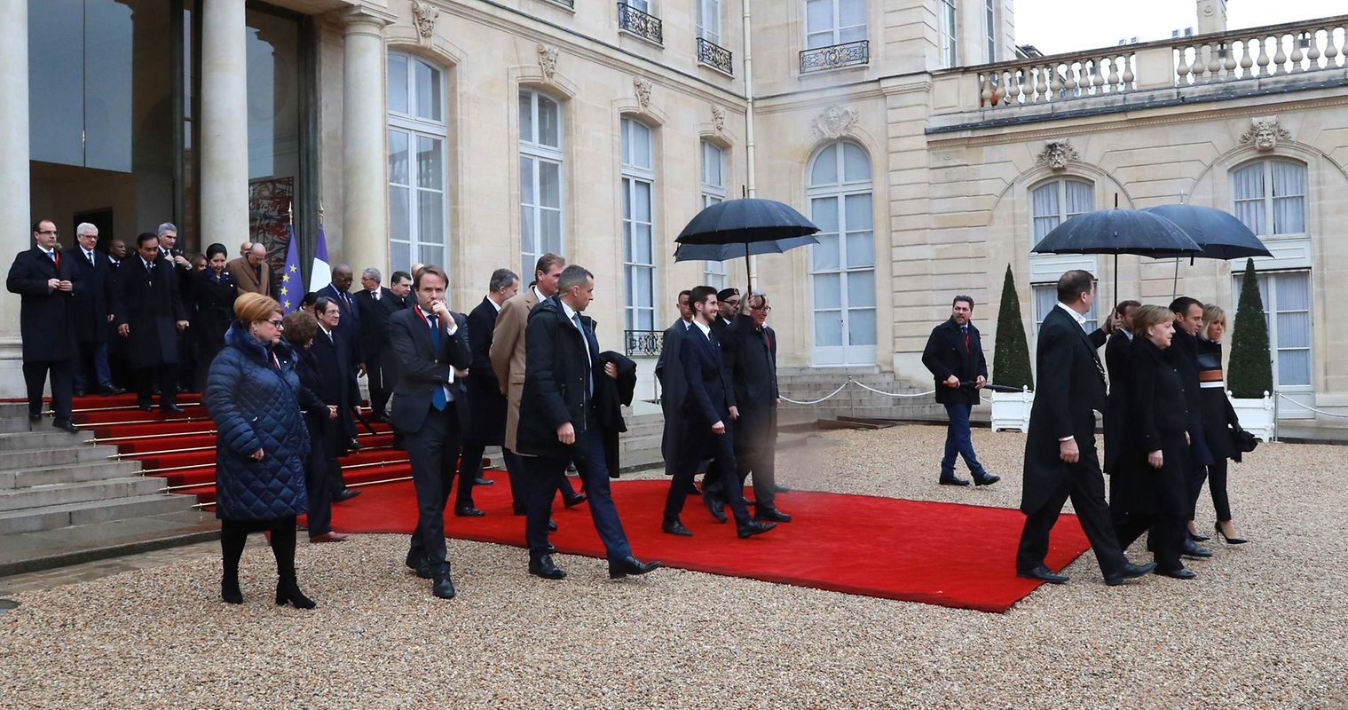 French President Emmanuel Macron (R), his wife Brigitte Macron, German Chancellor Angela Merkel and other heads of state and government leave the Elysee Palace in Paris on November 11, 2018 for the Arc de Triomphe prior to the start of commemorations marking the 100th anniversary of the 11 November 1918 armistice, ending World War I. (Photo by JACQUES DEMARTHON / AFP)