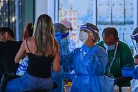 Holidaymakers on a motorbike (L) returning from Sardinia by ferry undergo a compulsory drive-through swab test on August 23, 2020 at the port of Civitavecchia, northwest of Rome, during the COVID-19 infection, caused by the novel coronavirus. - Italy has recorded 1,071 new cases of coronavirus in the last 24 hours, breaking the symbolic barrier of 1,000 cases per day for the first time since May 12, according to an official report published on August 22, 2020. "61% (of these new cases) are linked to holiday returns," and more specifically 45% (97 cases) concern returns from the island of Sardinia, which had been spared by the first wave of the virus but where the comings and goings of careless tourists and revellers have contributed to the spread of the virus. (Photo by Vincenzo PINTO / AFP)