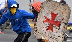 Opposition demonstrators use a makeshift shield as they clash with security forces during a protest against the government of President Nicolas Maduro on the anniversary of the 1958 uprising that overthrew the military dictatorship, in Caracas on January 23, 2019. - Venezuela's National Assembly head Juan Guaido declared himself the country's "acting president" on Wednesday during a mass opposition rally against leader Nicolas Maduro. (Photo by Yuri CORTEZ / AFP)