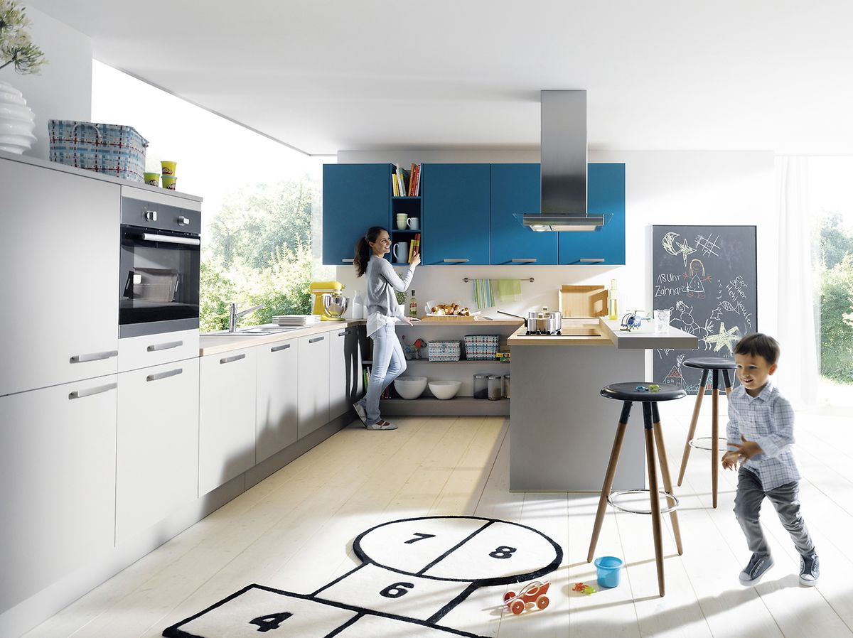 Drei Farben reichen: Man kann zum Beispiel einzelne Küchenschränke in Blau, die anderen in einem hellen Grauton wählen. Die hölzerne Arbeitsplatte ist der dritte Farbton im Raum. 
