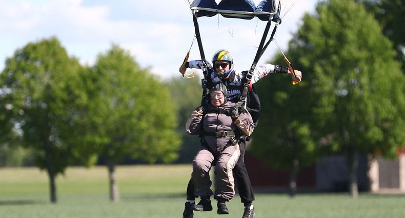 103-year-old Rut Larsson from Mj�lby and her tandem partner Joackim Johansson from Link�ping's parachute club complete their parachute jump on a field in Motala, Sweden, on May 29, 2022. - The 103-year-old Swedish woman set the world record for the oldest person to complete a tandem parachute jump, saying she planned to celebrate "with a little cake". Larsson, who is 103 years and 259 days old, beat the previous record of 103 years and 181 days. (Photo by Jeppe GUSTAFSSON / TT News Agency / AFP) / Sweden OUT