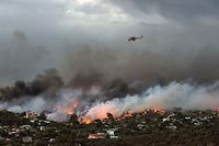 A firefighting helicopter flies over a wildfire raging in the town of Rafina near Athens, on July 23, 2018. 
At least five people have died and more than 20 have been injured as wild fires tore through woodland and villages around Athens on Monday, while blazes caused widespread damage in Sweden and other northern European nations. More than 300 firefighters, five aircraft and two helicopters have been mobilised to tackle the "extremely difficult" situation due to strong gusts of wind, Athens fire chief Achille Tzouvaras said.   / AFP PHOTO / ANGELOS TZORTZINIS