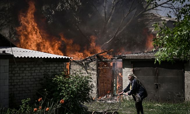 An elderly woman walks away from a burning garage after shelling in the city of Lysytsansk in eastern Ukrainian's Donbas region on Monday.