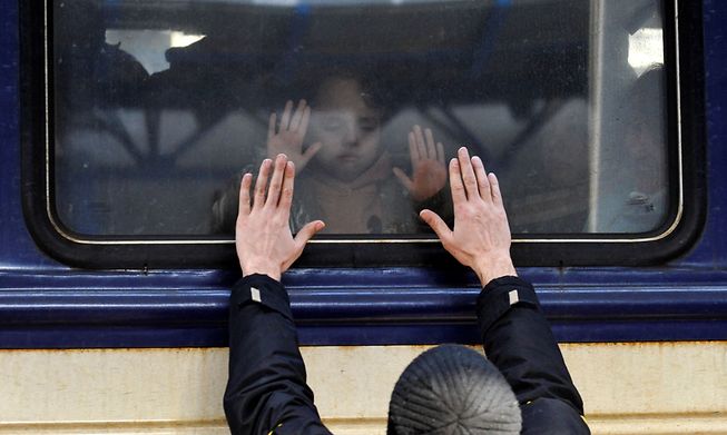 A man gestures to a young girl in front of an evacuation train at Kyiv central train station