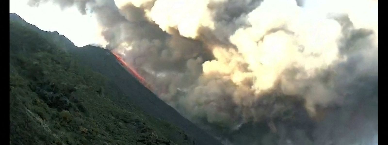 Ein Lavastrom fließt an der Flanke des Vulkans herunter.