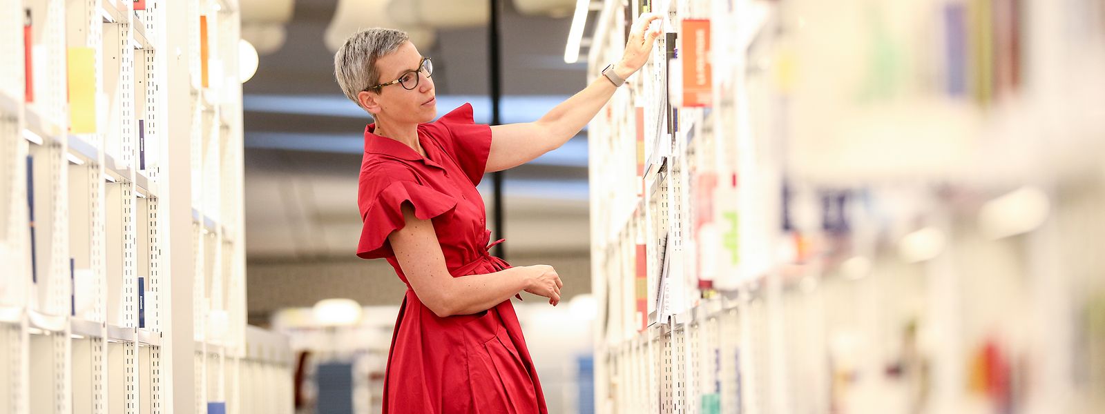 Sam Tanson beim Durchstöbern der Bücherregale im neuen Gebäude der Nationalbibliothek in Kirchberg. Dieses soll am 30. September seine Türen offiziell öffnen.