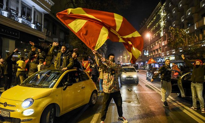 Supporters wave national flags in Skopje as they celebrate the victory of North Macedonia's team during the UEFA European qualifiers play-off on 12 November