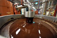 (FILES) This file photograph taken on July 8, 2013, shows hot chocolate before being moulded at the Barry Callebaut chocolate factory in Wieze, eastern Flanders. - Swiss group Barry Callebaut, the world's largest cocoa and chocolate company, said on June 30, 2022, that it had halted chocolate production at its Wieze (Belgium) factory, billed as the world's largest, after salmonella was found in a batch on June 26. (Photo by GEORGES GOBET / AFP)