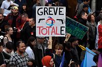 TOPSHOT - A protester holds a placard reading 'Total strike' -a play on the French energy giant TotalEnergies-  during a rally against soaring living costs and climate inaction called by French left-wing coalition NUPES (New People's Ecologic and Social Union) in Paris on October 16, 2022. (Photo by JULIEN DE ROSA / AFP)