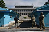 TOPSHOT - UNC (United Nations Command) soldiers (R) and a South Korean soldier (L) stand guard before North Korea's Panmon Hall (rear C) and the military demarcation line separating North and South Korea, at Panmunjom, in the Joint Security Area (JSA) of the Demilitarized Zone (DMZ) on October 4, 2022. (Photo by Anthony WALLACE / AFP)