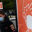 A youth wearing a protective face mask passes by a sign asking to wear a mask in Rennes, western France, on September 7, 2020. (Photo by Damien MEYER / AFP)