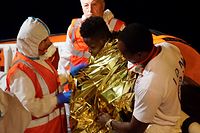 This handout photo taken on June 27, 2019 and released on June 28, 2019 by NGO Sea Watch shows rescuers evacuating a young migrant (C) for medical reason from the Sea Watch 3 rescue ship off the coast of Lampedusa. - A sick 19-year-old migrant and his young brother have been evacuated late on June 27 from a Sea-Watch rescue boat banned by Italy from docking on the island of Lampedusa, as another 40 migrants are still onboard. The stand-off between Sea-Watch 3 and the Italian authorities escalated on June 26 when the vessel entered Italian waters despite a threat of hefty fines from far-right Interior Minister Matteo Salvini. (Photo by Handout / Sea Watch / AFP) / RESTRICTED TO EDITORIAL USE - MANDATORY CREDIT "AFP PHOTO / SEA WATCH" - NO MARKETING NO ADVERTISING CAMPAIGNS - DISTRIBUTED AS A SERVICE TO CLIENTS --- NO ARCHIVE ---
