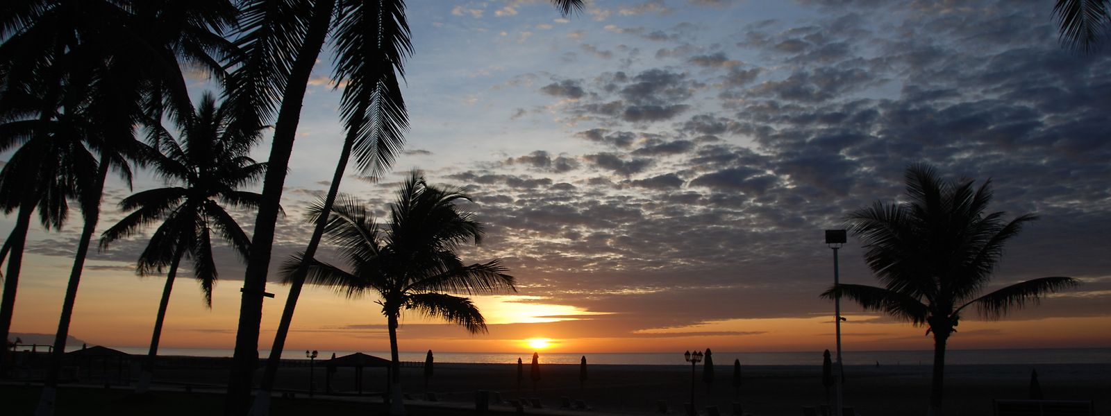 Der Sonnenaufgang am Strand bei Salalah taucht den Himmel und die Landschaft in atemberaubende Farben. 
