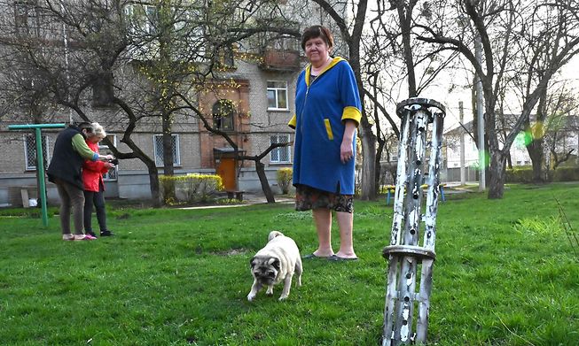 A Kharkiv resident walks her dog and looks at a missile fragment in a yard of residential buildings in Ukraine, on Friday.