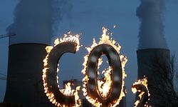 ARCHIV - 17.11.2008, Hessen, Hanau: Mit einem brennenden "CO 2-Zeichen" demonstrieren Mitglieder der Umweltschutzorganisation Greenpeace vor dem Kohlekraftwerk Staudinger in Hanau gegen den Schadstoffausstoß des Kraftwerkes. (zu dpa «UN-Bericht: Klimawandel gefährdet Nachhaltigkeitsziele») Foto: Boris Roessler/dpa +++ dpa-Bildfunk +++