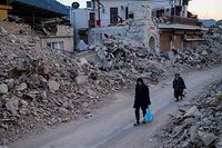 People walk past collapsed buildings in Antakya, southern Turkey on February 20, 2023. - A 7.8-magnitude earthquake hit near Gaziantep, Turkey, in the early hours of February 6, followed by another 7.5-magnitude tremor just after midday. The quakes caused widespread destruction in southern Turkey and northern Syria and has killed more than 44,000 people. (Photo by Yasin AKGUL / AFP)