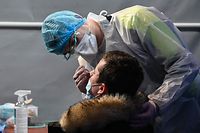 A health worker takes a nasal swab on a man to perform a Covid-19 test in a testing centre at the Dunkirk convention centre, as the French Prime minister asked for additional measures to curb the spread Covid-19 to be implemented in the city, on February 23, 2021. (Photo by DENIS CHARLET / AFP)