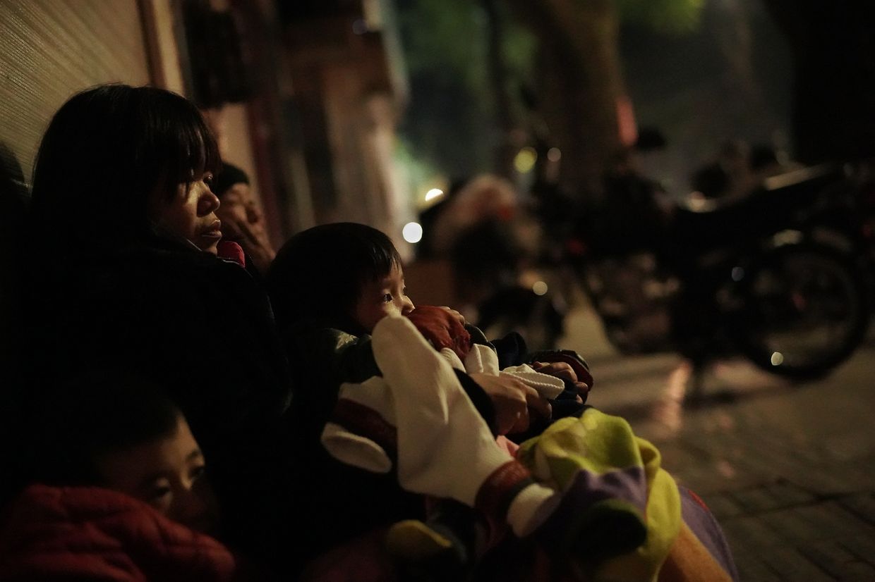 Eine Mutter, die nach einem Familienstreit obdachlos geworden ist, sitzt nachts mit ihren beiden kleinen Kindern auf der Straße. 