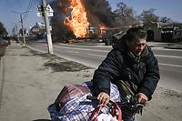 Um homem foge com os seus pertences durante um bombardemento na cidade nordeste de Kharkiv.