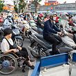   Hieu Luu (vorn) ist während der Hauptverkehrszeit unterwegs, ebenso wie unzählige Motorroller.  Sich in der Metropole fortzubewegen ist schon für Menschen ohne Handicap eine Herausforderung und noch mehr für Rollstuhlfahrer. 
