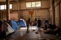 Migrants stand near tents in an abandoned building near the Kara Tepe camp, on the Greek Aegean island of Lesbos on September 16, 2020, after the Moria  migrant camp was destroyed by a fire on the night of September 8. - Six young Afghan men including two minors will face a prosecutor on Greece's Lesbos island on September 16 on suspicion of setting fires that destroyed Europe's largest migrant camp, leaving over 12,000 people homeless. (Photo by ANGELOS TZORTZINIS / AFP)