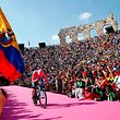 A fan waves the flag of Ecuador (L) as overall race winner Team Movistar rider Ecuador's Richard Carapaz reacts as he enters the arena after competing in stage twenty-one, the final stage of the 102nd Giro d'Italia - Tour of Italy - cycle race, a 17km individual time-trial in Verona on June 2, 2019. (Photo by Luk BENIES / AFP)