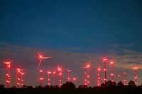 Die roten Positionslichter an Windenergieanlagen erhellen den Nachthimmel und die Landschaft. 