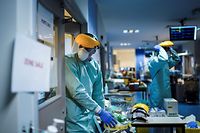 Medical workers put on their protective gears before working on March 27, 2020, at the unit for coronavirus COVID-19 infected patients at the Erasme Hospital in Brussels. (Photo by Kenzo TRIBOUILLARD / AFP)