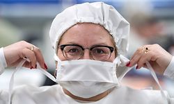 24.03.2020, Sachsen, Geyer: Solveig Brändl vom Textilunternehmen Brändl in Geyer zeigt Schutzkleidung und eine Mundschutzmaske, die hier im Unternehmen gefertigt werden. Die Masken und die Kleidung bestehen aus einem antibakteriellen Stoff, in dem Fäden aus reinem Silber eingewebt sind. Mit dem innovativen technischen Textil kämpft das Unternehmen aus dem Erzgebirge seit längerem gegen Krankenhauskeime. Was vielen Krankenhäusern bislang zu teuer war, wird in der Coronakrise interessant. Jetzt stellt der Betrieb auf Mundschutzmasken und Schutzkleidung um. Foto: Hendrik Schmidt/dpa-Zentralbild/ZB +++ dpa-Bildfunk +++