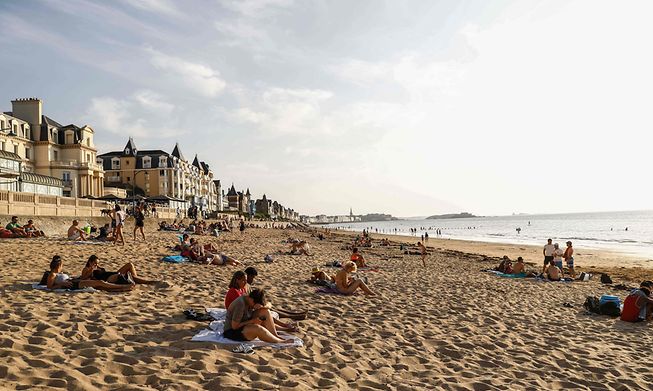 Tourists sunbathe on a beach by the sea in Saint-Malo, western France, in July