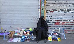An Iranian street vendor wearing a protective mask amid the novel coronavirus pandemic, sits by her display of goods on a street of the capital Tehran, on May 09, 2020. (Photo by ATTA KENARE / AFP)