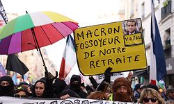 A demonstrator holds a placard which reads "Macron, grave-digger of our retirement" during a rally, called by left-wing La France Insoumise (LFI) party and Youth organizations, to protest against French President's pension reform, in Paris on January 21, 2023. - The pensions plan, presented by French President Emmanuel Macron's government last week, would raise the retirement age for most from 62, to 64 and would increase the years of contributions required for a full pension. The French Interior Ministry put the total number of protesters that marched against France's President's plan to extend the retirement age at 1.2 million, on January 19, 2023, including 80,000 in Paris. (Photo by Thomas SAMSON / AFP)
