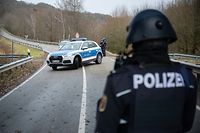 31.01.2022, Rheinland-Pfalz, Mayweilerhof: Polizeibeamte stehen an einer Absperrung an der Kreisstraße 22 rund einen Kilometer von dem Tatort, an dem zwei Polizeibeamte durch Schüsse getötet wurden. Foto: Sebastian Gollnow/dpa +++ dpa-Bildfunk +++