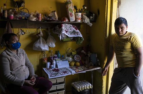 Honduran asylum seekers Ramon Funes (R) and Bernard Bejarano, who wears a protective masks due to a recent respiratory infection, talk at the room they rent in Tijuana, Baja California State, Mexico, on April 3, 2020 during the novel coronavirus, COVID-19, pandemic. - Bejarano and Funes had their case resolution appointment on a migration court in San Diego on March 10, but it was postponed indefinitely due to the COVID-19 pandemic. Thousands of migrants overcrowding shelters or begging in the streets in Mexican cities along the US border are living in fear as the novel coronavirus spreads in the population and screening interviews for asylum seekers are being suspended. (Photo by Guillermo ARIAS / AFP)